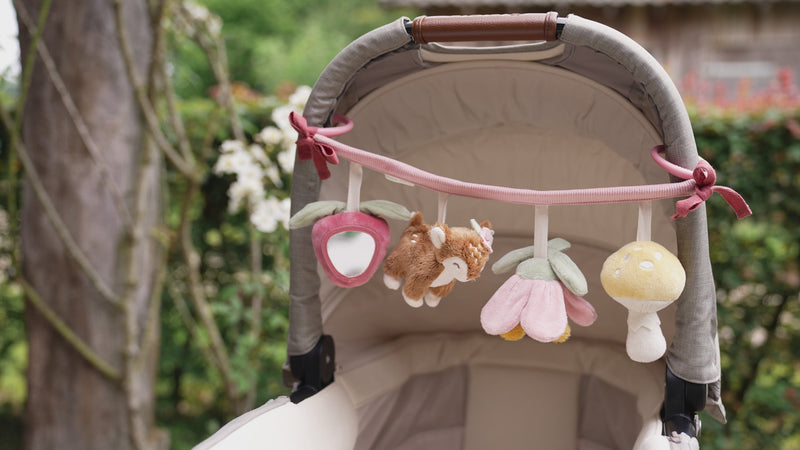 A baby is playing with the Little dutch stroller toy chain.