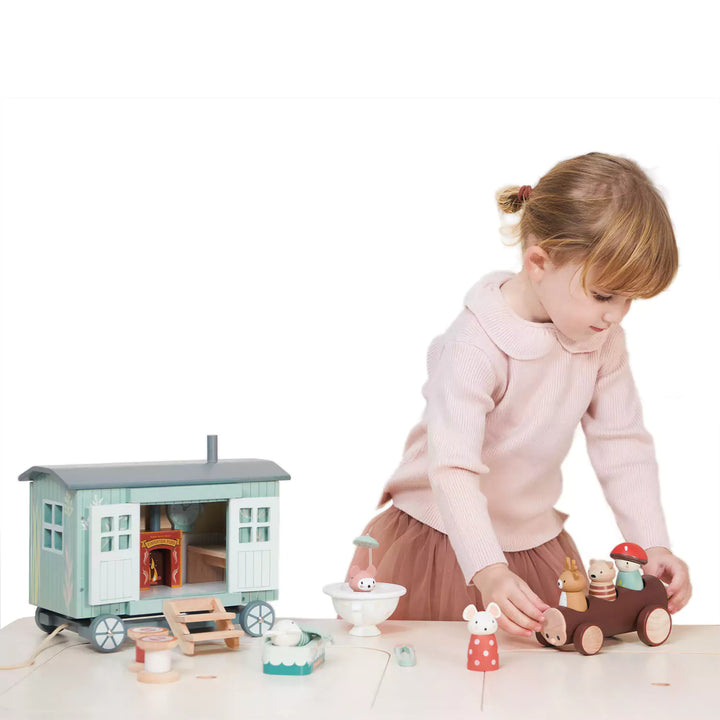 A girl is playing with shepherd's hut toy