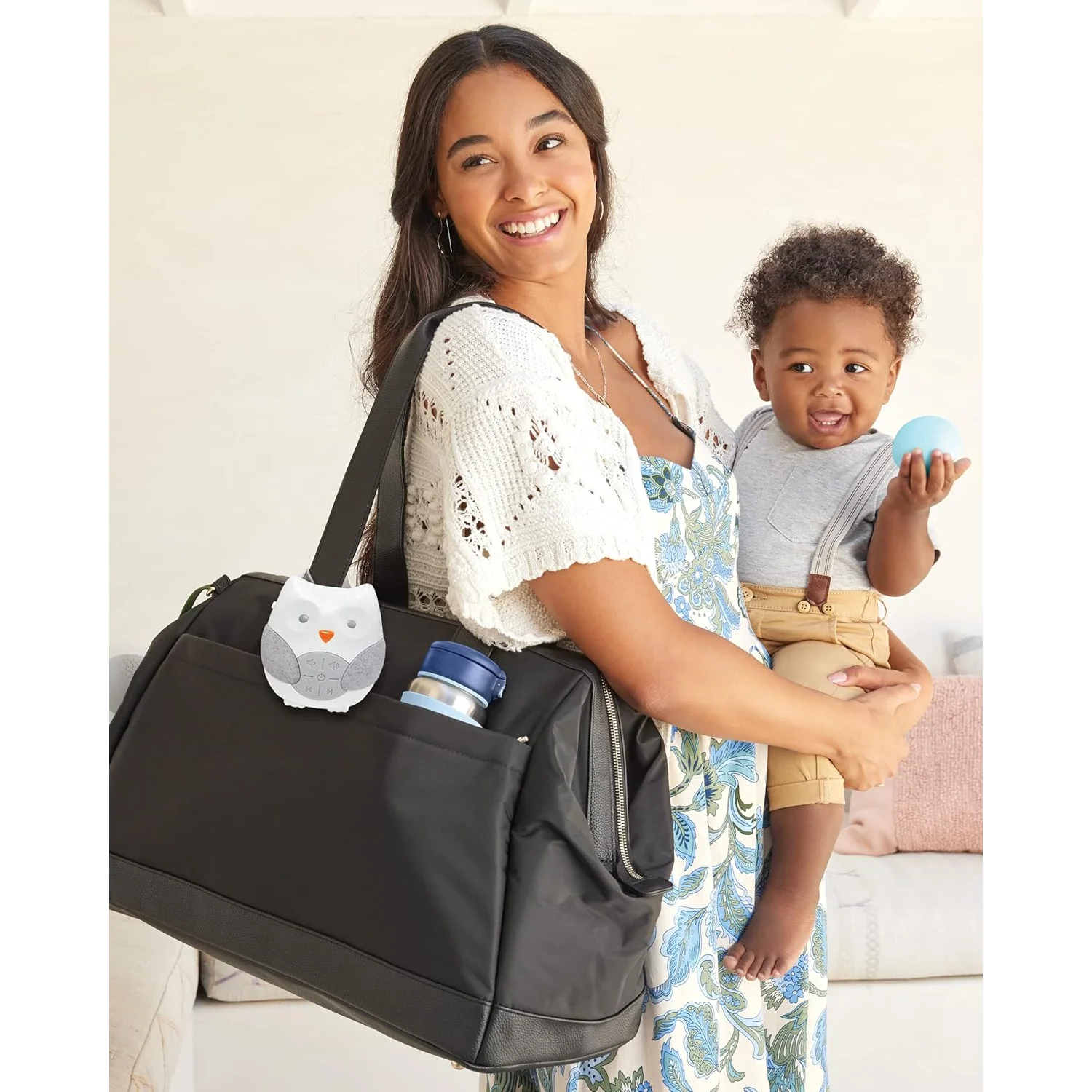 Woman holding a black diaper bag with a baby in a sling
