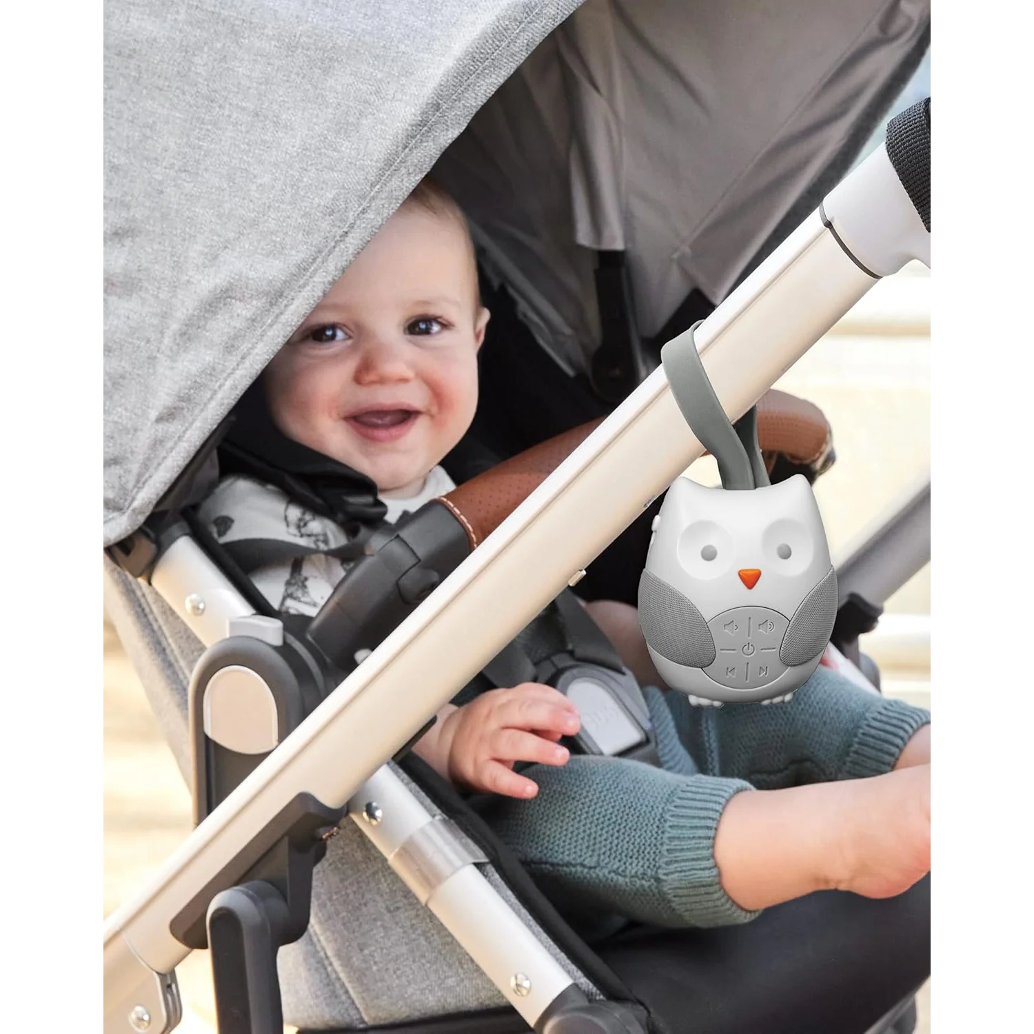 Baby in a stroller with an owl-shaped toy attached