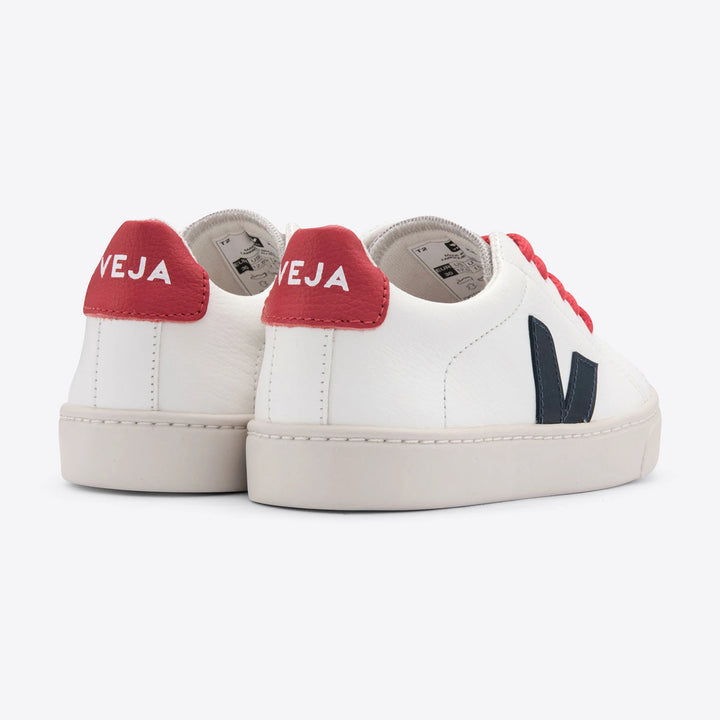 Eco-friendly Veja kids' trainers in white with blue and red details, made with chrome-free leather and recycled materials, including a second pair of laces.