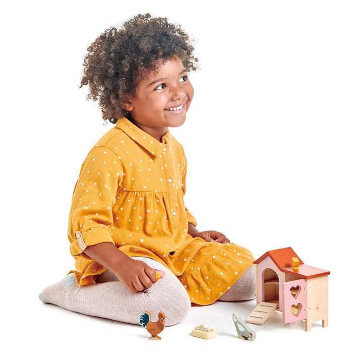 A girl playing with wooden chicken coop family playset