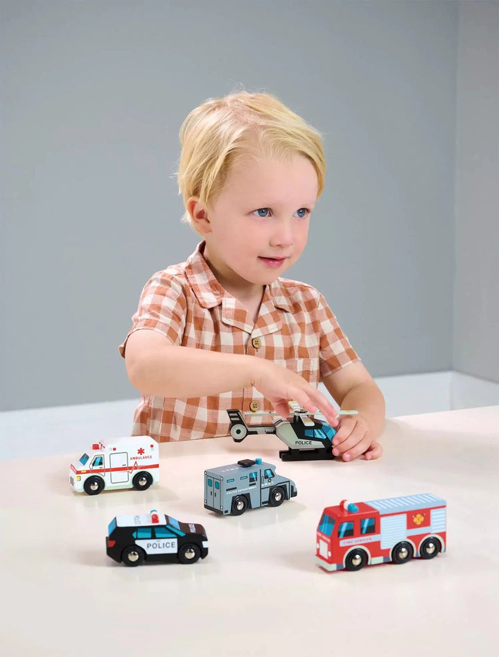 A boy is playing with emergency vehicles toy set