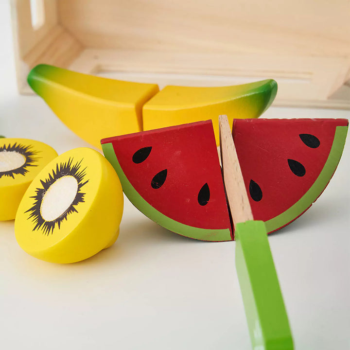 A colorful set of wooden fruits and vegetables in a wooden crate, for pretend play cutting.